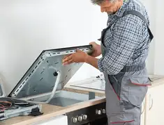 Appliance repair technician installing a built-in cooktop in San Francisco, CA