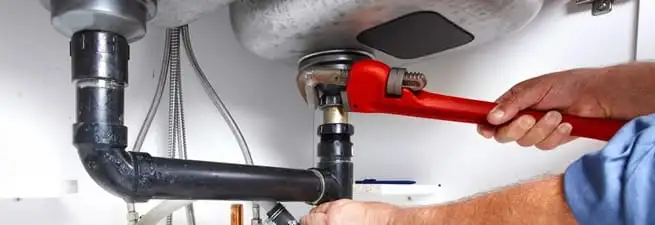 Garbage disposal repair technician tightening the sink drain and disposal connection in San Francisco, CA