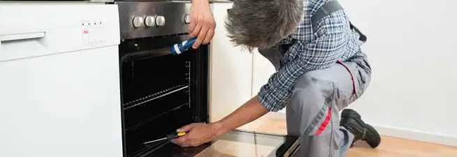 Oven repair technician inspecting and servicing an electric oven in San Francisco, CA