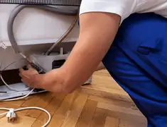 Appliance repair technician fixing refrigerator water line and connections in San Francisco, CA