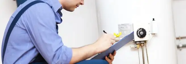 Water heater repair technician inspecting the unit and recording service notes in San Francisco, CA